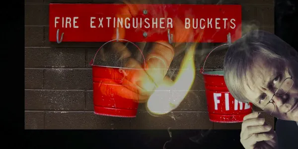 A hand with a lit match is superimposed over 2 fire extinguisher buckets, with a professorial looking man peering in from the right of the image.