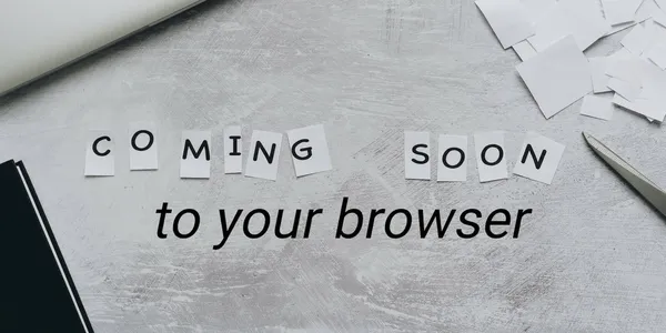 The sentence: coming soon to your browser is arranged in cut-up pieces of paper on a desk.