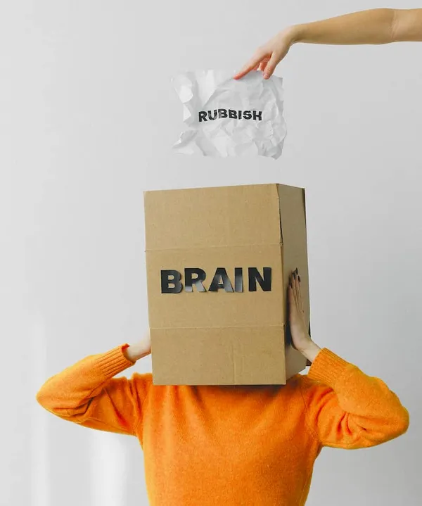 man with a box on his head saying brain and a hand dropping a piece of paper into the box with the word rubbish on it