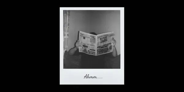 A polaroid photo of man behind a newspaper with the 'ahmm..' written on the margin.