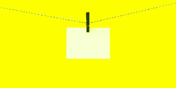 A blank note is clipped with a peg to a line.